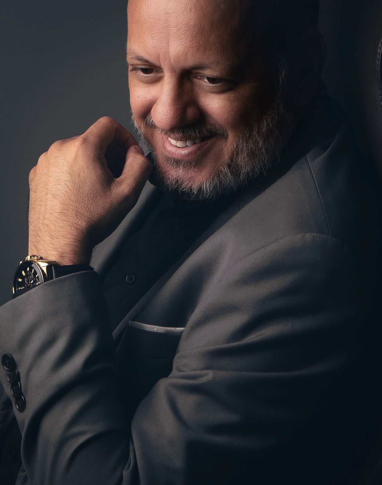 Raimundo Jùnior sorrindo, sentado e vestido de terno